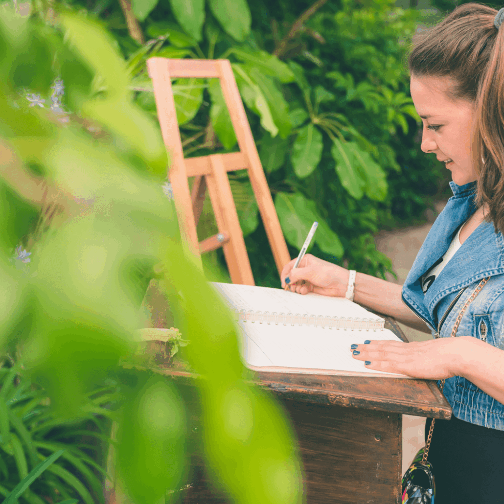 Teenager schreibt Wünsche in ein Gästebuch im Grünen.