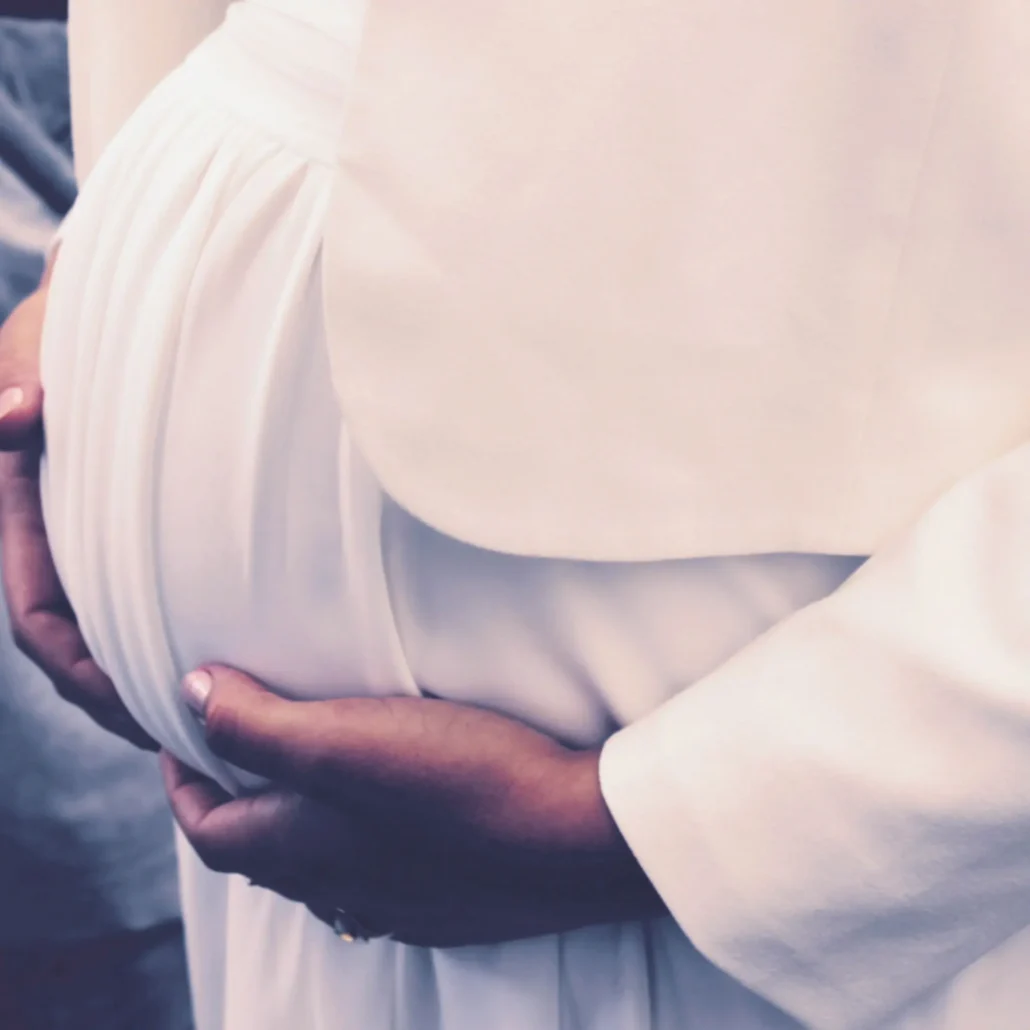 Schwangere Frau hält schützend die Hände auf ihren Babybauch: Vorfreude auf das neue Leben.